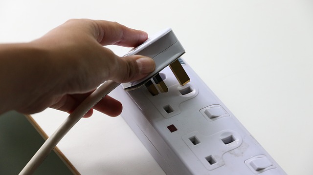 A person unplugging an electronic device from an outlet.